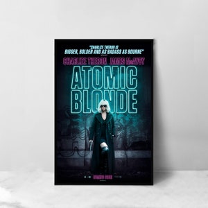 Puede incluir: Cartel de la película de acción "Atomic Blonde" protagonizada por Charlize Theron y James McAvoy. El cartel presenta a una mujer con un abrigo negro y gafas de sol de pie frente a una pared cubierta de grafitis. El título "Atomic Blonde" está escrito en letras azules de neón.