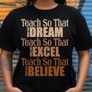 Può includere: Una maglietta nera con il testo "Teach So That they can DREAM Teach So That they can EXCEL Teach So That they can BELIEVE" in colore marrone.