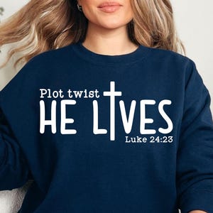 May include: A navy blue sweatshirt with white text that reads "Plot twist HE LIVES Luke 24:23".