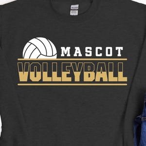 Op de afbeelding: Een zwart sweatshirt met een gouden en witte volleybalafbeelding en de tekst "Mascot Volleyball".