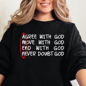 May include: A black sweatshirt with the text "AGREE WITH GOD MOVE WITH GOD END WITH GOD NEVER DOUBT GOD" printed on the front. The text is circled in red.