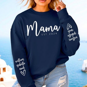 Op de afbeelding: Navyblauwe trui met de tekst "Mama Est 2024" op de voorkant. De mouwen hebben witte tekst die "William Isabella Noah" op de ene mouw en "You are my everything" op de andere mouw staat.