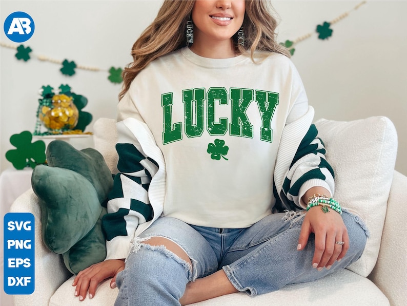 May include: A white sweatshirt with green text that says "LUCKY" and a green four-leaf clover. The sweatshirt has a white and green striped pattern on the sleeves.