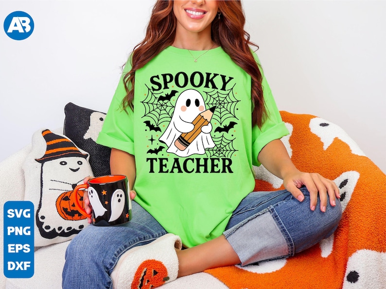 May include: A lime green t-shirt with the words "Spooky Teacher" and a graphic of a ghost holding a pencil. The shirt is paired with blue jeans. A black mug with white ghost designs is visible.