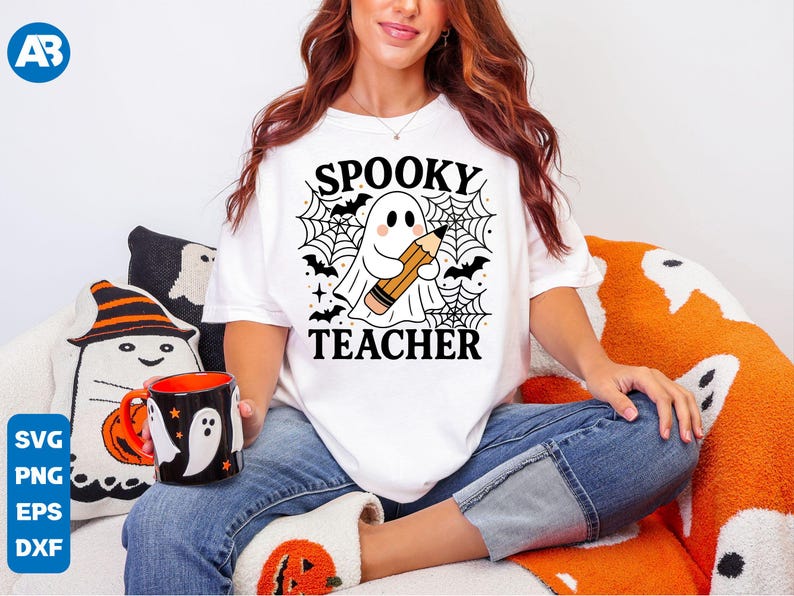 May include: White t-shirt with the text "SPOOKY TEACHER" and a graphic of a ghost holding a pencil, surrounded by bats and spiderwebs. The image also includes a black mug with ghost and pumpkin designs.