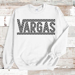 May include: White sweatshirt with a black and white checkered design that says "VARGAS" in black letters.