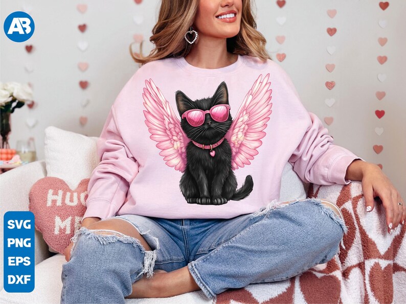 May include: A pink sweatshirt with a black cat wearing pink sunglasses and angel wings. The cat is wearing a black collar with a heart charm.