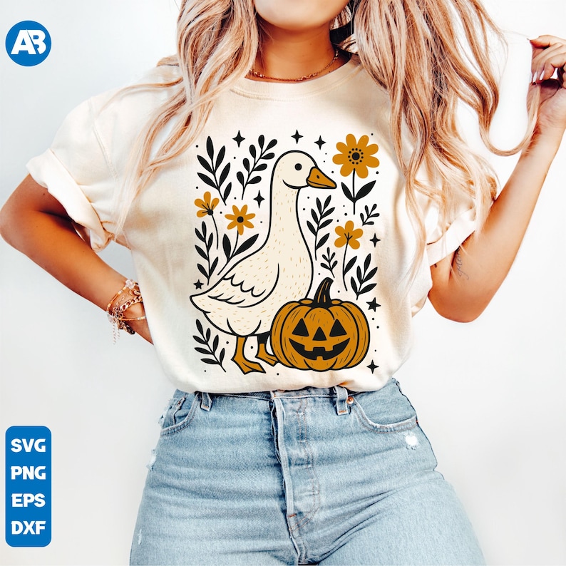May include: Cream-colored t-shirt featuring a whimsical illustration of a goose, a jack-o'-lantern, and floral elements in black and gold. The design includes the text "SVG, PNG, EPS, DXF" in a blue box. A fun, seasonal graphic tee.
