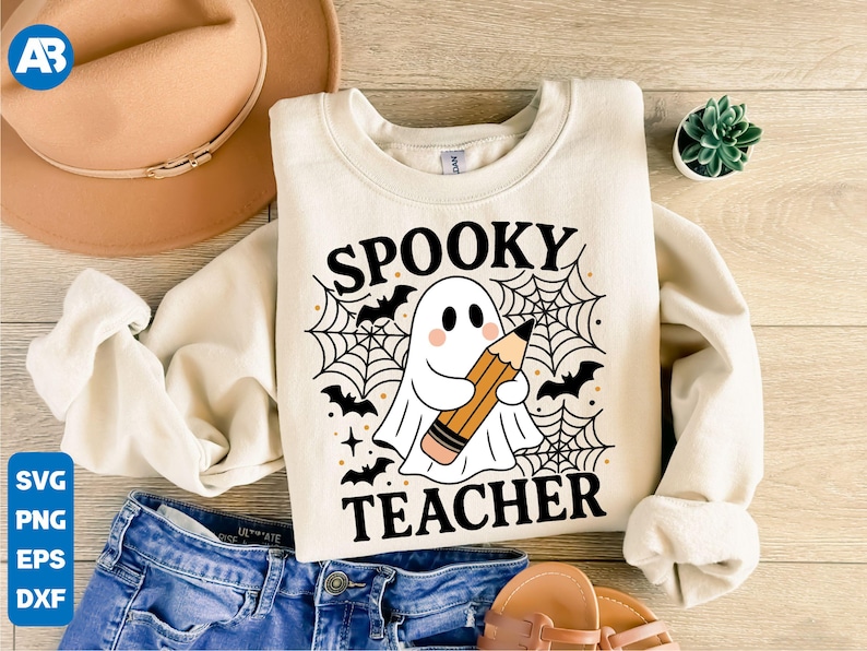 May include: Cream-colored sweatshirt with the words "SPOOKY TEACHER" and a ghost holding a pencil. The design includes bats, spiderwebs, and stars. The sweatshirt is paired with blue jeans, a hat, and sandals.