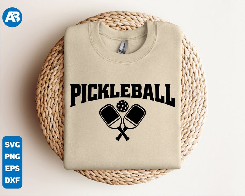 May include: A beige sweatshirt with the text "Pickleball" in black letters and a graphic of two crossed pickleball paddles and a ball.