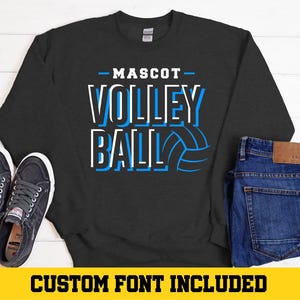 May include: A dark gray sweatshirt with the text "MASCOT VOLLEYBALL" in blue and white lettering. The text is outlined in white and the word "VOLLEYBALL" has a volleyball graphic next to it.