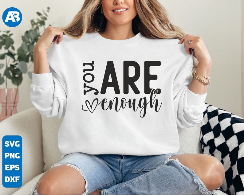 May include: White sweatshirt with the text "You Are Enough" in black lettering with a small heart symbol.