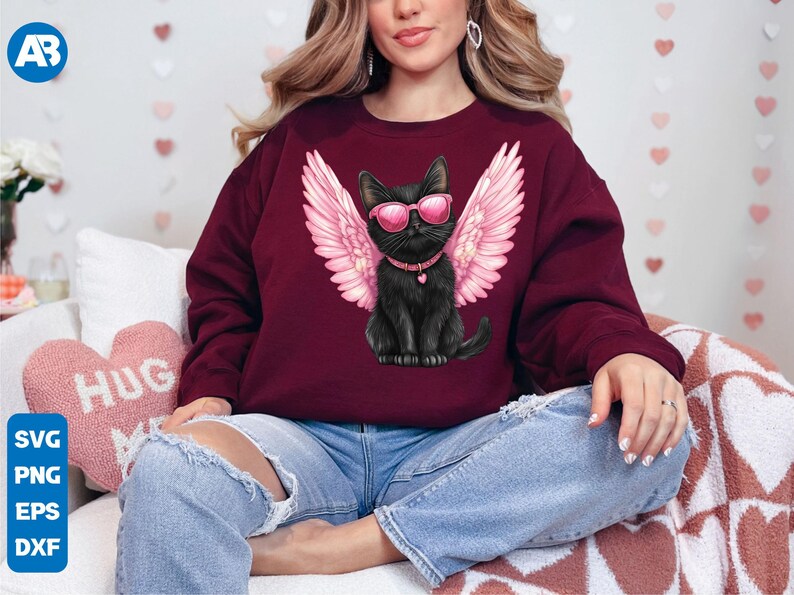 May include: A maroon sweatshirt with a black cat wearing pink angel wings and sunglasses. The cat is wearing a black collar with a silver heart charm.