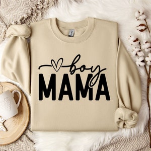 May include: A beige sweatshirt with a black graphic that says "boy mama" with a small heart above the word "boy".