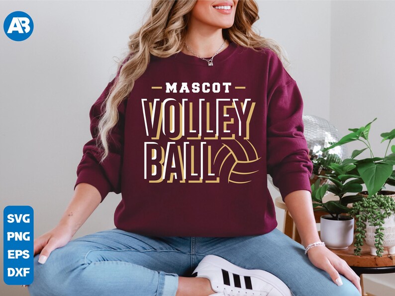 May include: A maroon sweatshirt with the text "Mascot Volleyball" in white and gold lettering. A gold volleyball graphic is to the right of the text.
