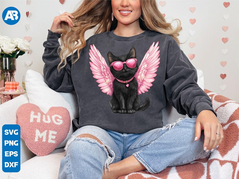 May include: A black sweatshirt with a graphic of a black cat wearing pink sunglasses and pink angel wings. The cat is wearing a black collar with a silver heart charm. The sweatshirt is on a person wearing blue jeans.