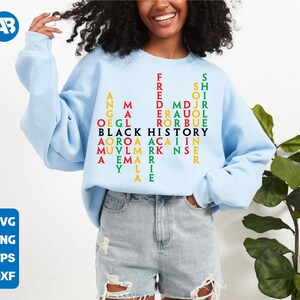 May include: A light blue sweatshirt with a word search design that reads "Black History" in black letters. The words are arranged in a grid pattern with red, green, and yellow letters.