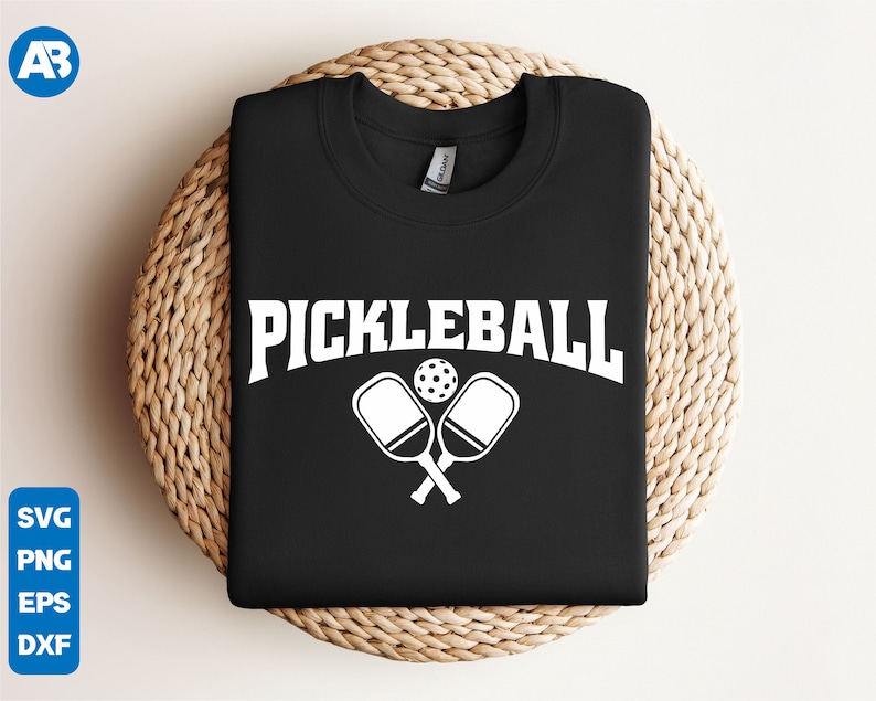 May include: Black t-shirt with white text that says "Pickleball" and a graphic of two crossed pickleball paddles and a ball.