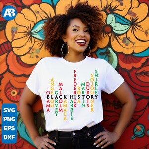 May include: A white t-shirt with a graphic design featuring the words "Black History" in a red, green, and yellow colour scheme. The graphic design is a word puzzle with names of prominent Black figures.