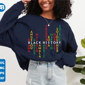 May include: A navy blue sweatshirt with a word puzzle design featuring the words "Black History" in red, green, and yellow letters. The words are arranged in a grid pattern, creating a visual representation of the phrase.