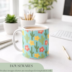 K&ouml;nnte beinhalten: Eine wei&szlig;e Keramiktasse gef&uuml;llt mit einem hellbraunen Getr&auml;nk. Die Tasse hat einen t&uuml;rkisfarbenen Hintergrund mit einem Muster aus gelben, roten und gr&uuml;nen Kakteen und Blumen. Das Wort "HOUSEWARES" steht unten.