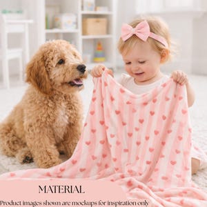 May include: A baby holding a pink and white striped blanket with red hearts. A golden doodle dog is sitting next to the baby. The word "MATERIAL" is at the bottom of the image.