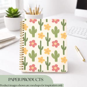 K&ouml;nnte beinhalten: Ein cremefarbenes Spiralnotizbuch mit einem sich wiederholenden Muster aus gr&uuml;nen Kakteen, rosa und gelben Blumen. Das Notizbuch hat eine goldene Spiralbindung. Der Text "PAPER PRODUCTS" befindet sich am unteren Rand des Bildes.