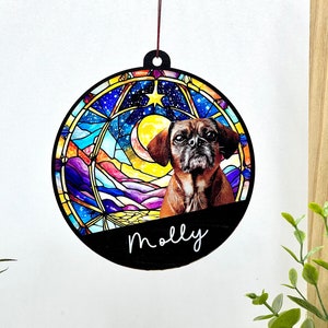 May include: A round wooden ornament with a stained glass design featuring a colorful night sky, a crescent moon, and a star. A brown dog with black eyes is peeking out from behind the moon. The ornament is personalized with the name "Molly".