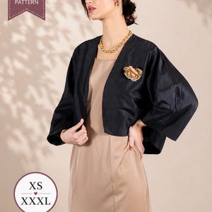 May include: A black cropped jacket with wide three-quarter length sleeves worn over a sleeveless beige dress. The jacket features an open front and is adorned with a beige fabric flower brooch. The image includes text reading PDF SEWING PATTERN and XS heart XXXL.