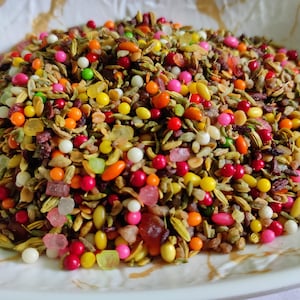 Può includere: Una ciotola di mix di snack indiano colorato, chiamato "pan masala", con una varietà di ingredienti tra cui semi di finocchio, caramelle e frutta secca.