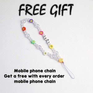 May include: A white beaded phone chain with colorful flower and smiley face charms. The chain has a purple string attached to it. The text "FREE GIFT" is at the top of the image. The text "LOVE" is on the chain. The text "Mobile phone chain Get a free with every order mobile phone chain" is at the bottom of the image.