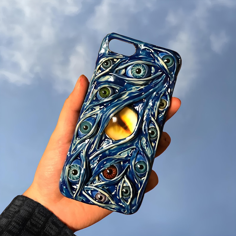 May include: A blue phone case with a design of multiple eyes and a large yellow eye in the center.