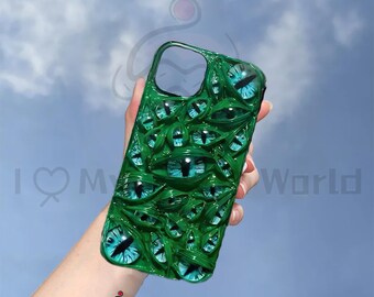 May include: Green phone case with a design of many blue eyes. The case is made of a glossy material and has a 3D effect.
