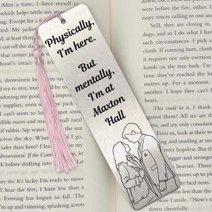 Puede incluir: Un marcapáginas rectangular de metal plateado con acabado cepillado y una borla rosa claro en la parte superior. El texto dice, Physically, I'm here. But mentally, I'm at Maxton Hall, junto a una ilustración de líneas de una pareja.