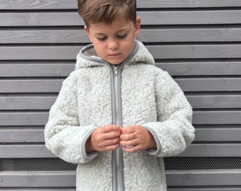 May include: A light grey, long-sleeved, hooded jacket made of a textured, fleece-like material. The jacket features a central vertical zip closure with a grey trim along the edges of the hood, the front opening, and the sleeve cuffs.