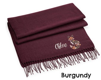 May include: Burgundy scarf with a decorative fox design and the name "Chloe" embroidered in white. The scarf has a fringed edge and is folded. The fox design features floral and leaf patterns.