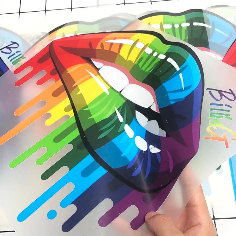 May include: A rainbow-colored graphic of a pair of lips with dripping paint. The lips are outlined in black and have a white interior. The dripping paint is in the colors of the rainbow, with red, orange, yellow, green, blue, indigo, and violet.