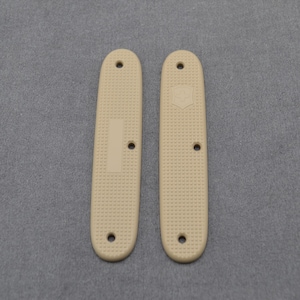 Peut inclure: Deux écailles en plastique couleur sable pour un couteau de poche. Les écailles ont une surface texturée et un petit trou en haut et en bas. Les écailles ont un petit logo sur le côté droit.