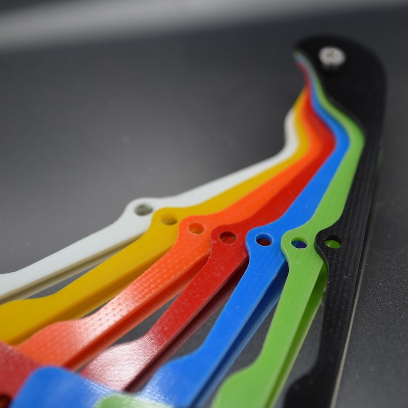 Pu&ograve; includere: Un set di pezzi di plastica colorati, tra cui bianco, giallo, arancione, rosso, blu, verde e nero. I pezzi sono disposti a ventaglio, con il pezzo nero in alto.