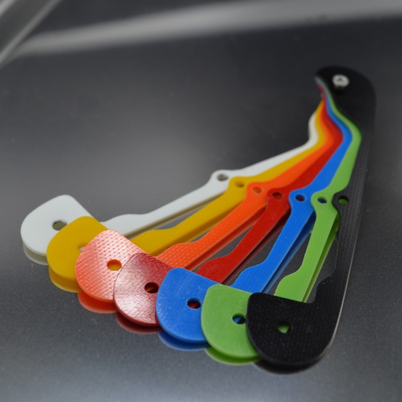 Pu&ograve; includere: Un set di sette pezzi di plastica colorati, ognuno con una forma e un design unici. I pezzi sono disposti a forma di arcobaleno, con il pezzo nero in basso.