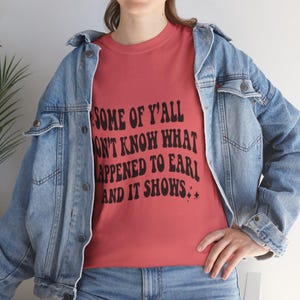Könnte beinhalten: Ein rotes T-Shirt mit einem schwarzen Grafikdruck, auf dem "Some of y'all don't know what happened to Earl and it shows." steht.