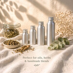 May include: Four silver aluminum bottles of varying sizes are arranged on a textured surface, with a small bowl of herbs and a glass jar in the background. The image includes the text "Perfect for oils, herbs & handmade blends."