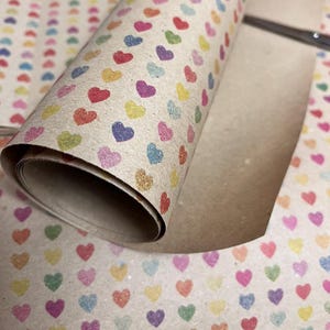 Recycled kraft wrapping paper with subtle heart pattern in soft colours.  Close up of paper in a roll