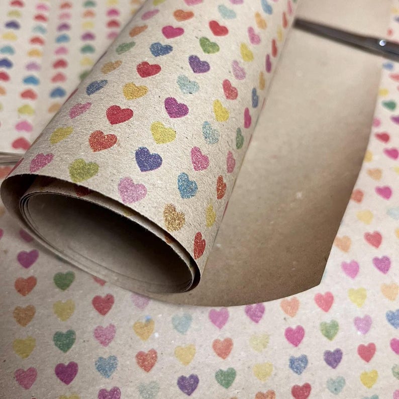 Recycled kraft wrapping paper with subtle heart pattern in soft colours.  Close up of paper in a roll