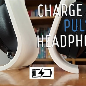 Peut inclure: Un support d'impression 3D blanc pour charger les écouteurs sans fil Sony Pulse 3D. Le support est en forme de ligne courbe avec une petite découpe en bas pour le câble de charge. Les écouteurs sont posés sur le support, le port de charge orienté vers le bas. Le texte "CHARGE YOUR PULSE 3D HEADPHONES!" est écrit en lettres blanches sur fond noir au-dessus du support. Une icône de batterie avec un éclair est en dessous du support.