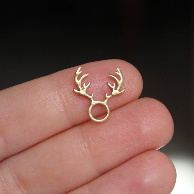 Puede incluir: Encanto de metal dorado en forma de asta de ciervo con un anillo en la base. El encanto es peque&ntilde;o y delicado, perfecto para agregar un toque de fantas&iacute;a a las joyas o las manualidades.