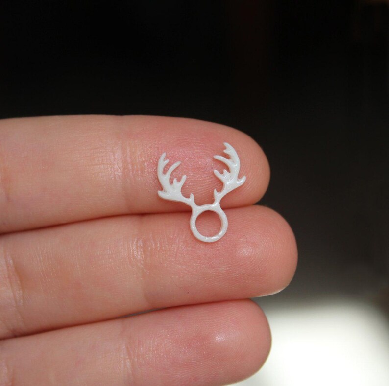 Puede incluir: Encanto de pl&aacute;stico blanco en forma de cuerno de reno con un anillo en el centro. El encanto es peque&ntilde;o y delicado.