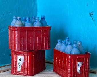 May include: Two red crates stacked on top of each other, filled with blue glass bottles. The top crate has the number "523" written on the side.