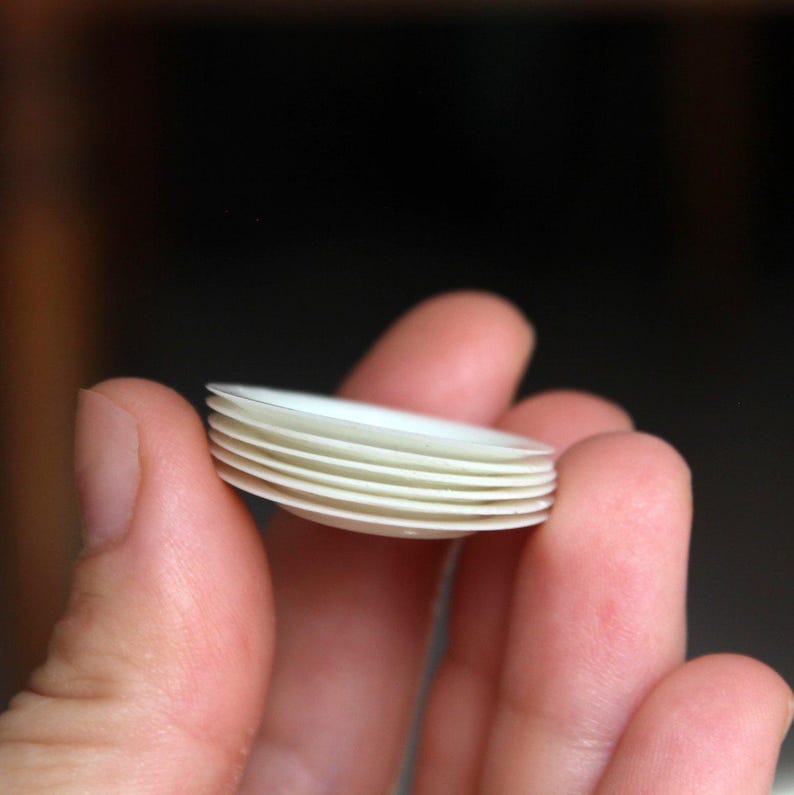 Puede incluir: Una pila de platos peque&ntilde;os de cer&aacute;mica blanca, probablemente para una casa de mu&ntilde;ecas o uso en miniatura.