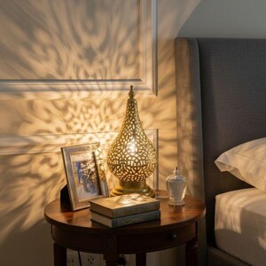 Handmade Moroccan brass lamp with intricate patterns, perfect for vintage bedside decor.